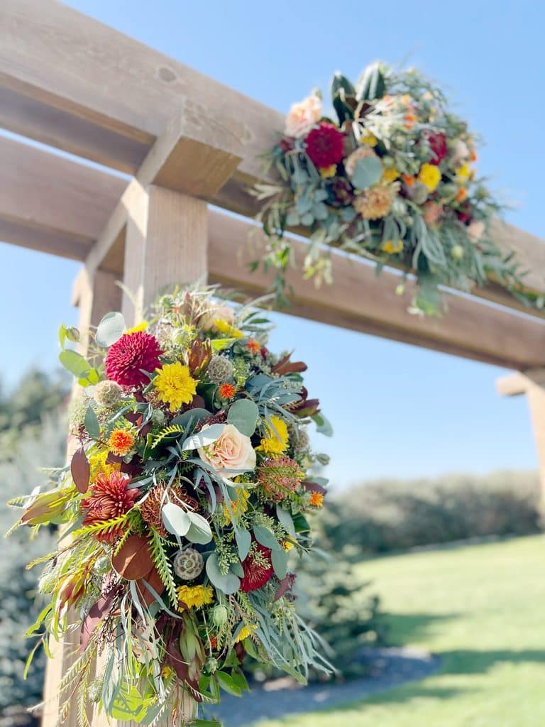 Colorful flower arrangement on wooden pergola against blue sky