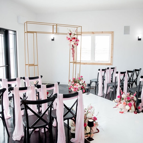 Pink floral-decorated wedding reception tables with black chairs