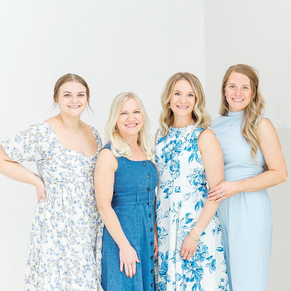 Four women smiling in blue dresses
